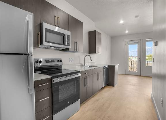 A modern kitchen with stainless steel appliances and wooden floors.