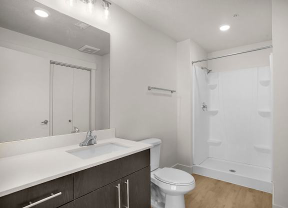 A white bathroom with a toilet, sink, and shower.