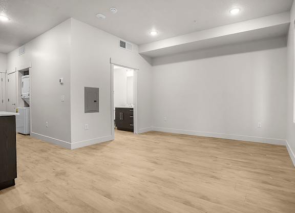 A large empty room with wooden flooring and white walls.