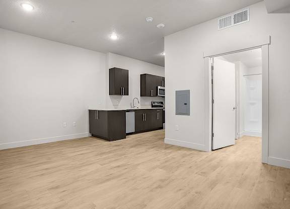 A kitchen with white walls and wooden floors.