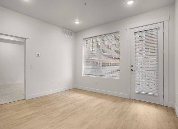 A room with wooden floors and white walls with two doors.