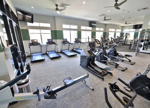 a large gym with cardio equipment and big windows in a building at Brookfield Apartments for rent in St. George, UT.