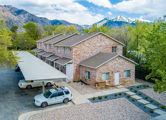A house with a car parked in front and mountains in the background.