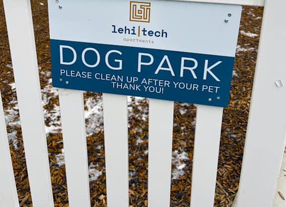 A sign in a dog park requests that people clean up after their pets.