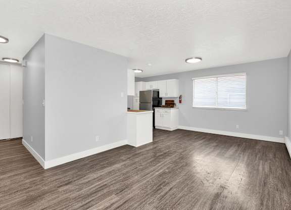 A spacious room with wooden flooring and white walls.