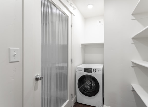 a small laundry room with a washing machine and a glass door