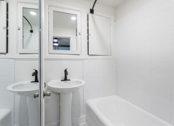 a white bathroom with two sinks and a tub and a shower