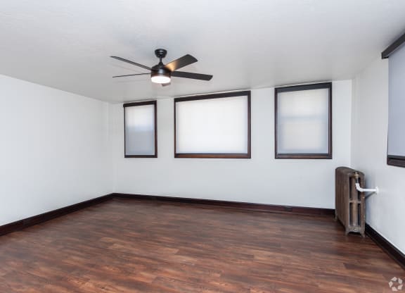 an empty living room with wood floors and a ceiling fan