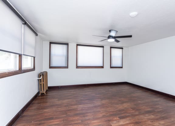 an empty living room with wood floors and a ceiling fan