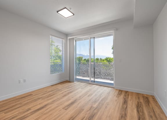 an empty living room with a sliding glass door to a balcony at Lotus Gallacher luxury apartments for rent in Salt Lake City, UT
