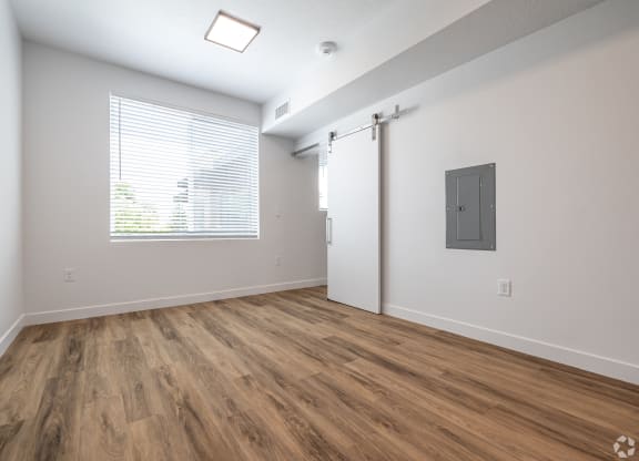 an empty living room with a window and wood flooring at Lotus Gallacher luxury apartments for rent in Salt Lake City, UT