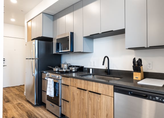 a kitchen with stainless steel appliances and black counter tops at Lotus Gallacher luxury apartments for rent in Salt Lake City, UT