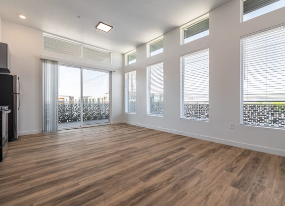 an empty living room with wood flooring and windows at Lotus Gallacher luxury apartments for rent in Salt Lake City, UT