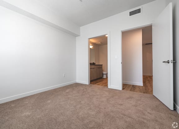 an empty living room with white walls and a door to a bathroom at Lotus Gallacher luxury apartments for rent in Salt Lake City, UT