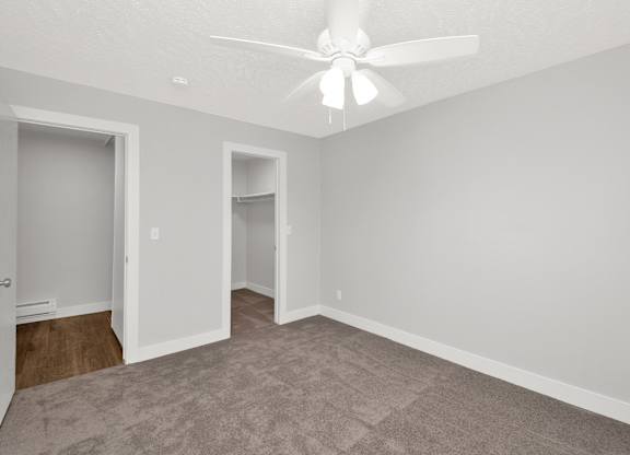 A room with a ceiling fan and carpeted floor.