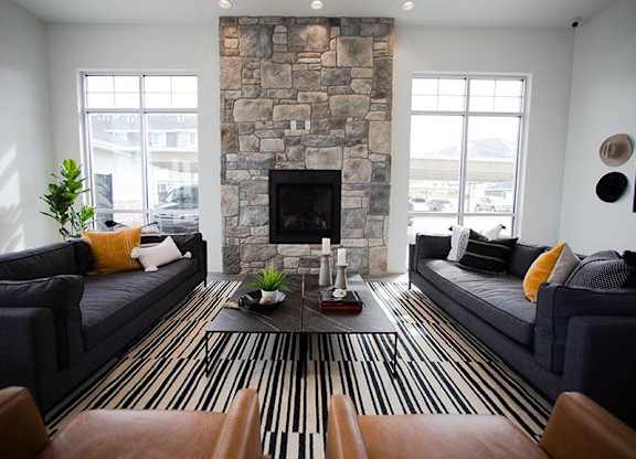 A living room with a stone fireplace and striped rug.