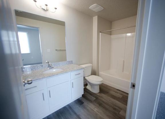 A bathroom with a toilet, sink, and mirror.