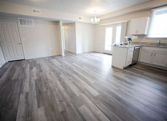 A spacious room with wood flooring and white walls.