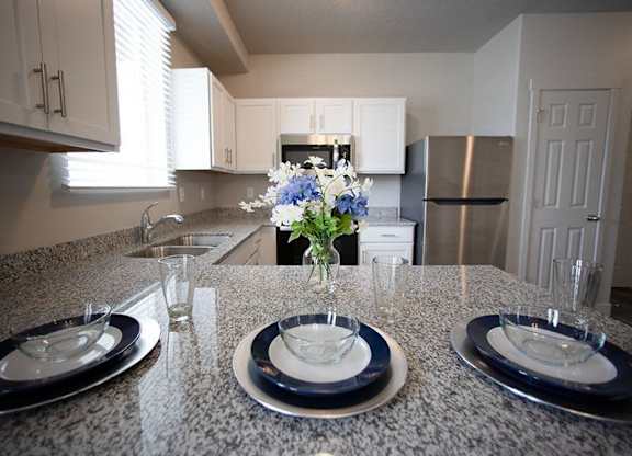 A kitchen with a granite countertop and a vase of flowers on it.