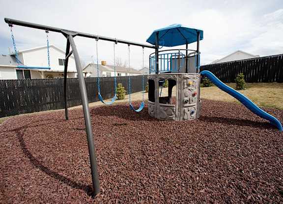 A playground with a blue slide and a grey structure.