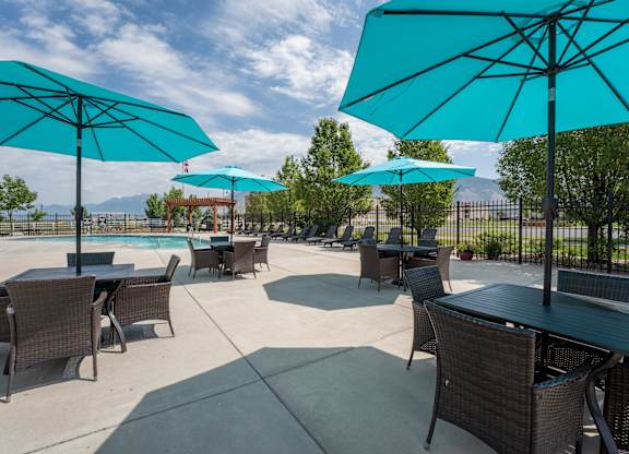 A patio with tables and chairs under blue umbrellas.
