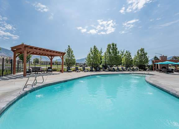 A large outdoor swimming pool with a wooden pergola.