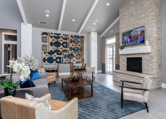 a large and modern fireplace area with couches and chairs and a tv at Outlook Apartments for rent in Springville and Provo, UT.