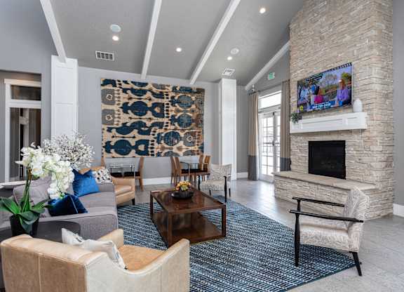 A living room with a stone fireplace and a large tapestry hanging on the wall.