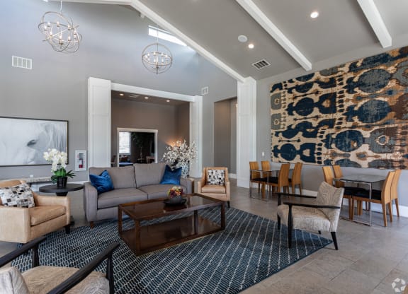 a large living room with couches, chairs, a table, and vaulted ceilings at Outlook Apartments for rent in Springville and Provo, UT.