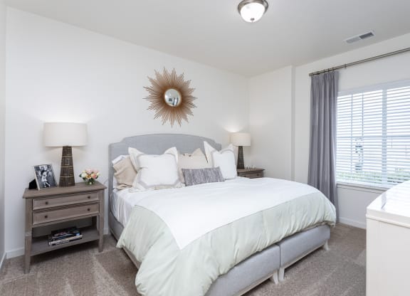 a bright and spacious bedroom with a large bed and a window at Outlook Apartments for rent in Springville and Provo, UT.
