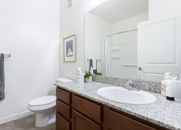 a bright bathroom with a sink, toilet and a mirror at Outlook Apartments for rent in Springville and Provo, UT.