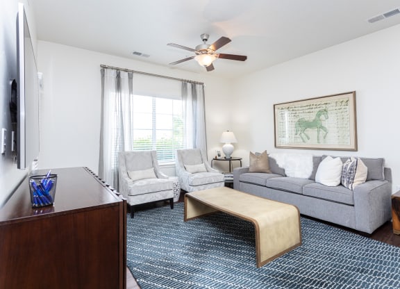a modern living room with a couch and two chairs and a ceiling fan at Outlook Apartments for rent in Springville and Provo, UT.