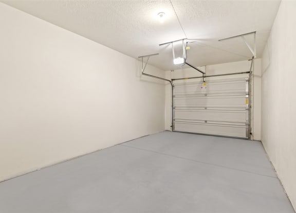 the interior of a garage with a white wall and a garage door at Outlook Apartments in Springville and Provo, Utah