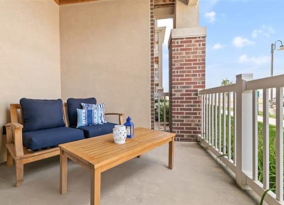 a patio with a couch and a table on a balcony from Outlook Apartments in Springville and Provo, Utah