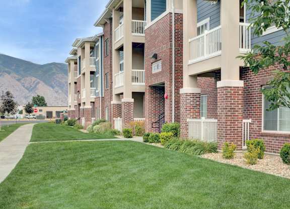 Apartment complex with green grass and trees in the background.
