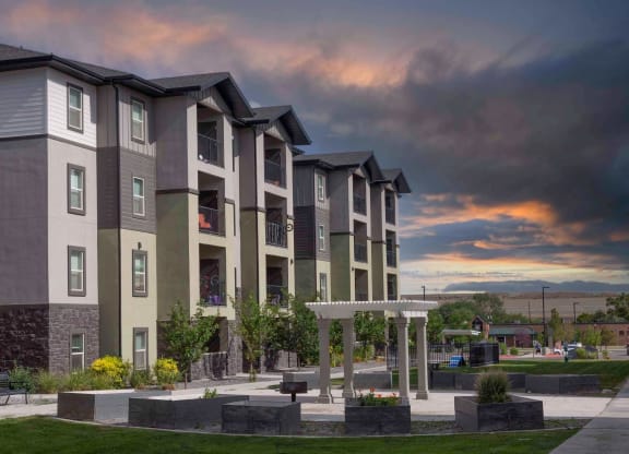 an exterior view of an apartment complex with a cloudy sky in the background