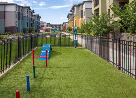 a grassy area with benches and a fence in front of an apartment complex