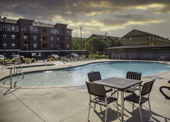 a swimming pool with a table and chairs and a building in the background