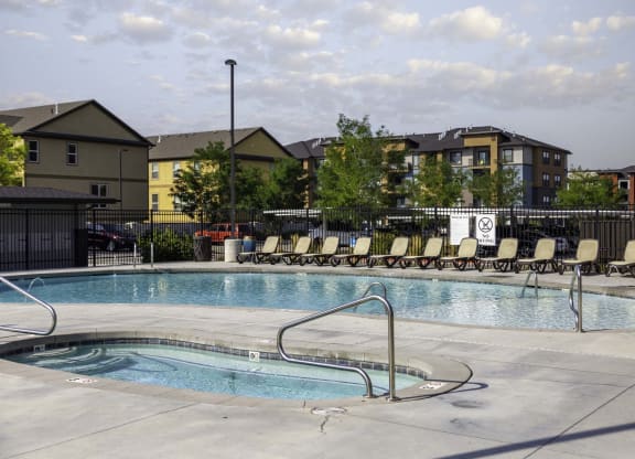 a swimming pool with chaise lounge chairs and buildings in the background