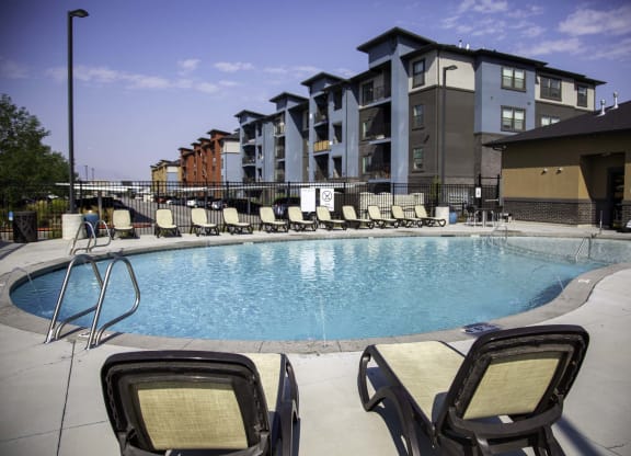 an outdoor pool with lounge chairs and a building in the background