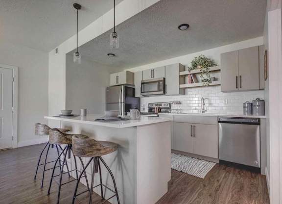 A kitchen with a white counter and bar stools.