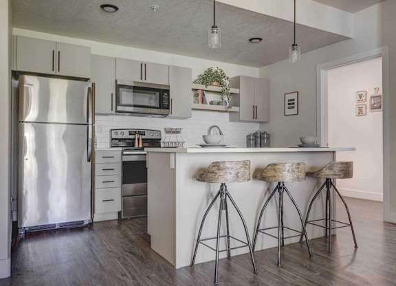 A kitchen with a bar stool and a refrigerator.