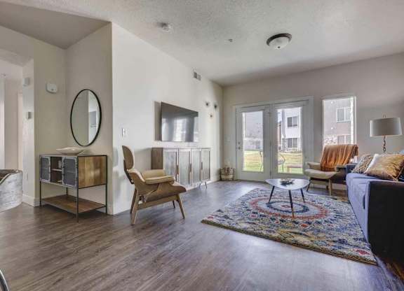 A living room with a rug, a chair, a table and a mirror.