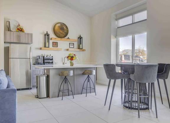 A kitchen with a grey table and chairs.