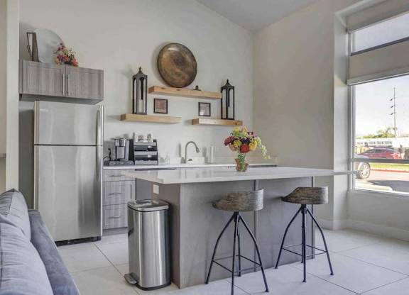 A modern kitchen with a refrigerator, stove, and bar stools.