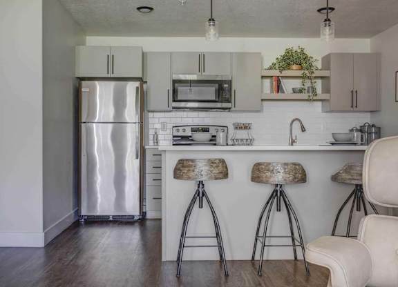 A kitchen with a white counter and bar stools.