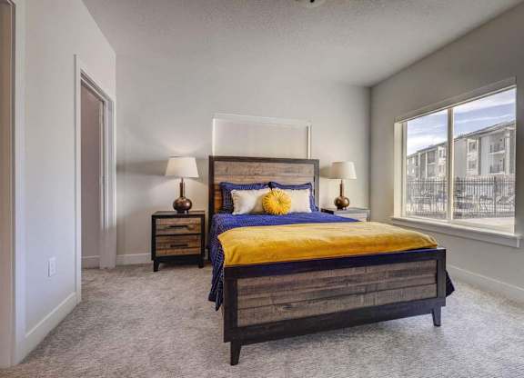 A bedroom with a bed, two lamps, and a nightstand.