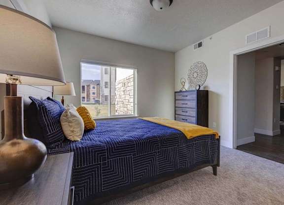 A bedroom with a bed, nightstand, and lamp.