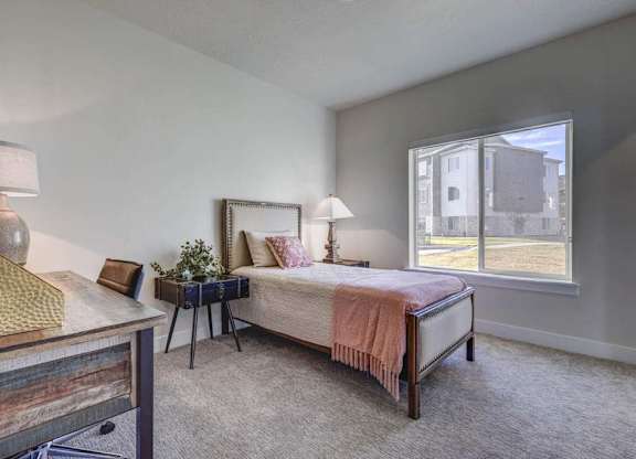 A bedroom with a bed, nightstand, and window.