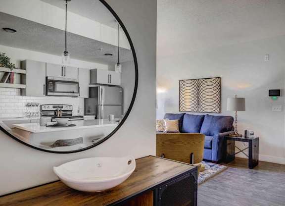 A modern bathroom with a round mirror and a wooden vanity.